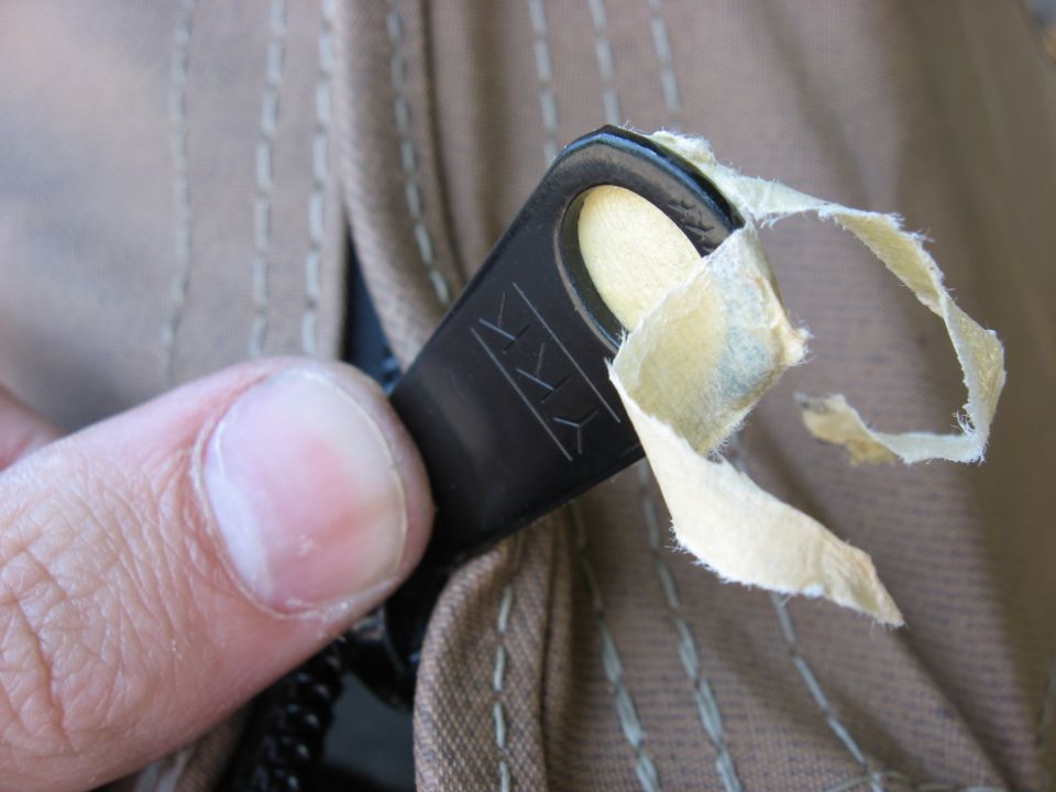 Zipper pull tab with YKK logo on tan fabric with torn tape