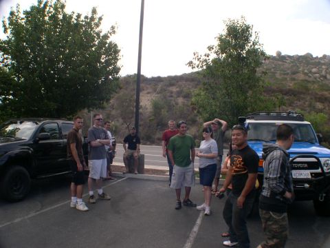 2007 Toyota FJ Cruiser - A group of people stand around two SUVs, a blue Toyota FJ Cruiser and a black Toyota Tacoma, in a parking lot.