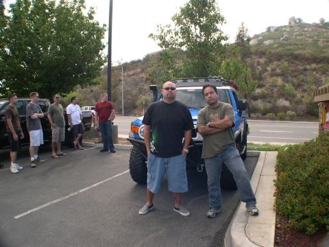 2007 Toyota FJ Cruiser - A group of people and vehicles gathered in a parking lot with a hilly landscape in the background.