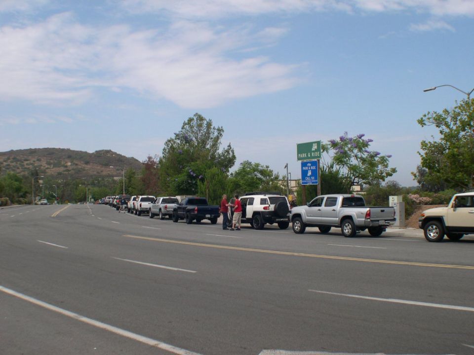 Line of Toyota FJ Cruisers and Tacomas parked on roadside with 'Park & Ride' sign