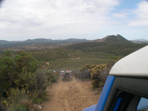 2007 Toyota FJ Cruiser - A convoy of SUVs navigates a dusty mountain trail under a cloudy sky.