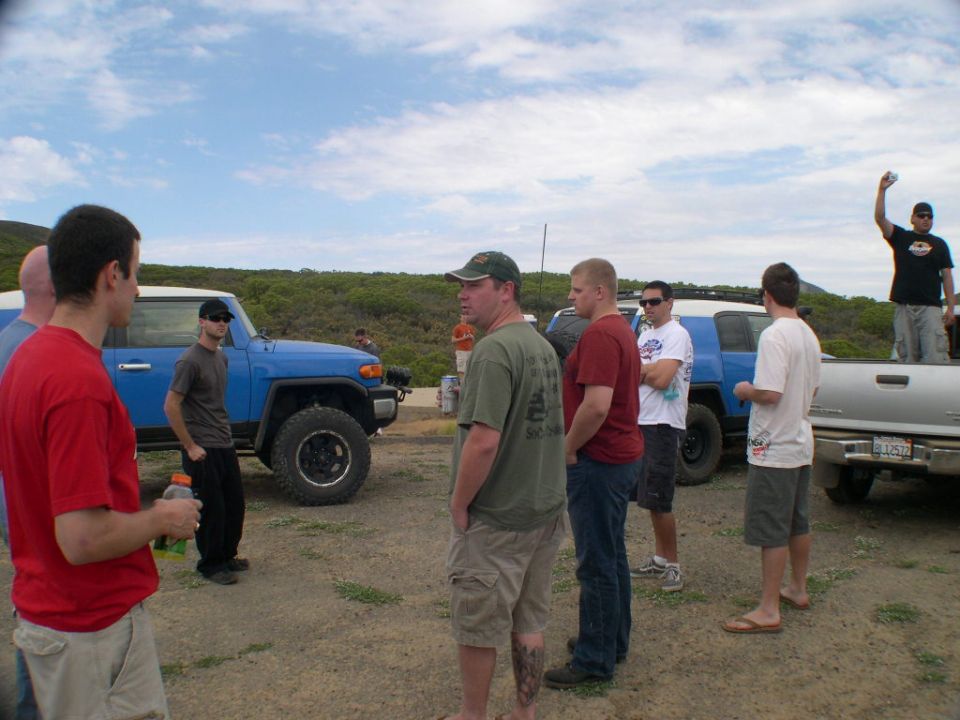 2007 Toyota FJ Cruiser parked on dirt with people around it, silver pickup truck also visible