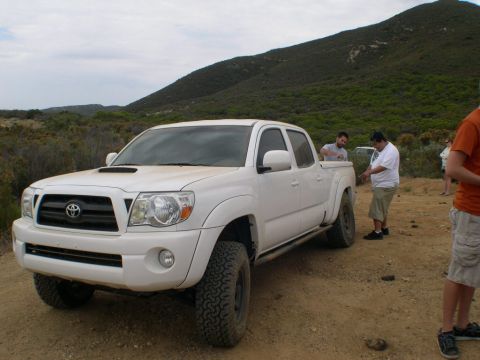 2007 Toyota FJ Cruiser - A white Toyota Tacoma pickup truck is parked on a dirt road with people around it.