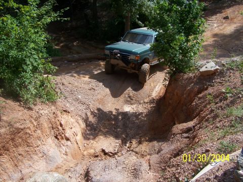 1979 Ford F-150 - A green pickup truck descends a challenging dirt path, its large tires gripping the terrain.