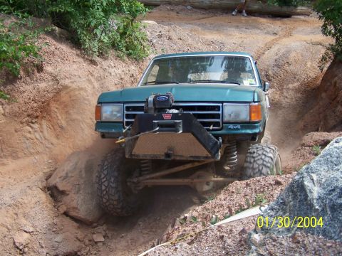 1979 Ford F-150 - Ford Bronco tackling a difficult off-road obstacle on a dirt trail.