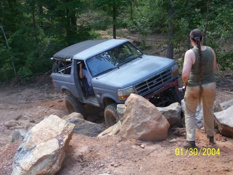 1979 Ford F-150 - A gray off-road truck navigates a challenging rocky path, with a woman observing.
