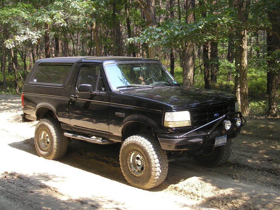 Black 1995 Ford Bronco with off-road tires and brush guard on dirt road