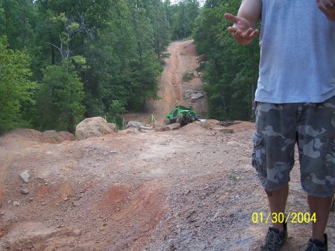 1979 Ford F-150 - A person stands in the foreground of a dirt trail with a green off-road vehicle on it.