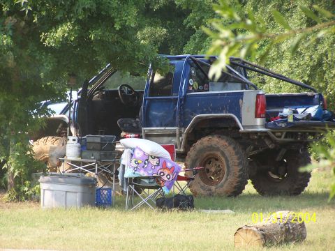 1979 Ford F-150 - Modified pickup truck with camping setup in a wooded area.