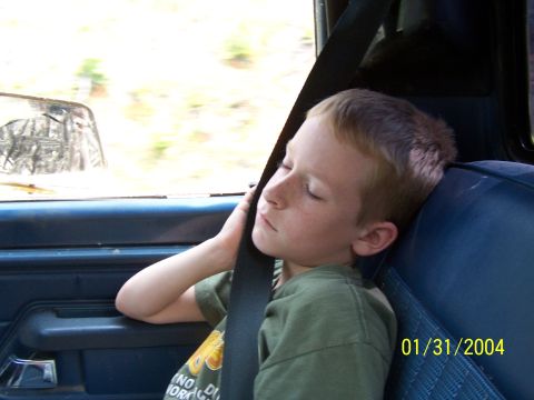 1979 Ford F-150 - Young boy asleep in a vehicle's passenger seat, secured by a seatbelt.
