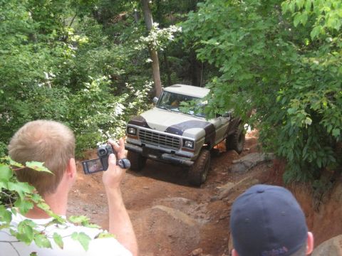 1979 Ford F-150 - A two-tone 1979 Ford F-150 navigates a challenging off-road trail surrounded by dense foliage.