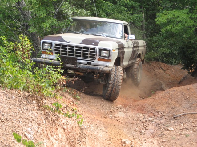 Ford pickup truck with camouflage paint going up a dirt hill