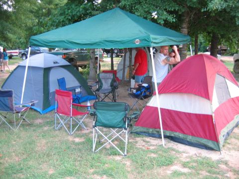 1992 Ford Mustang - People gathered at a campsite with tents and a canopy set up.