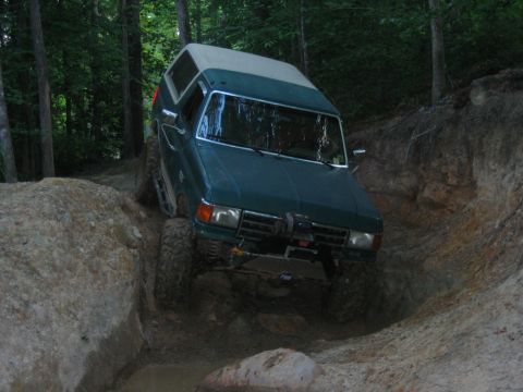 1992 Ford Mustang - This Ford Bronco is tackling a challenging off-road trail, with its tires digging into the dirt and mud.