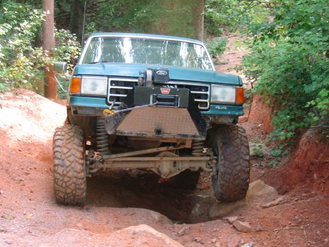 1992 Ford Mustang - This modified Ford truck is shown tackling a challenging off-road obstacle on a dirt path.
