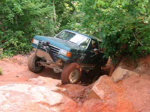 1992 Ford Mustang - A green Ford F-150 truck tackles a challenging off-road course with steep inclines and large rocks.