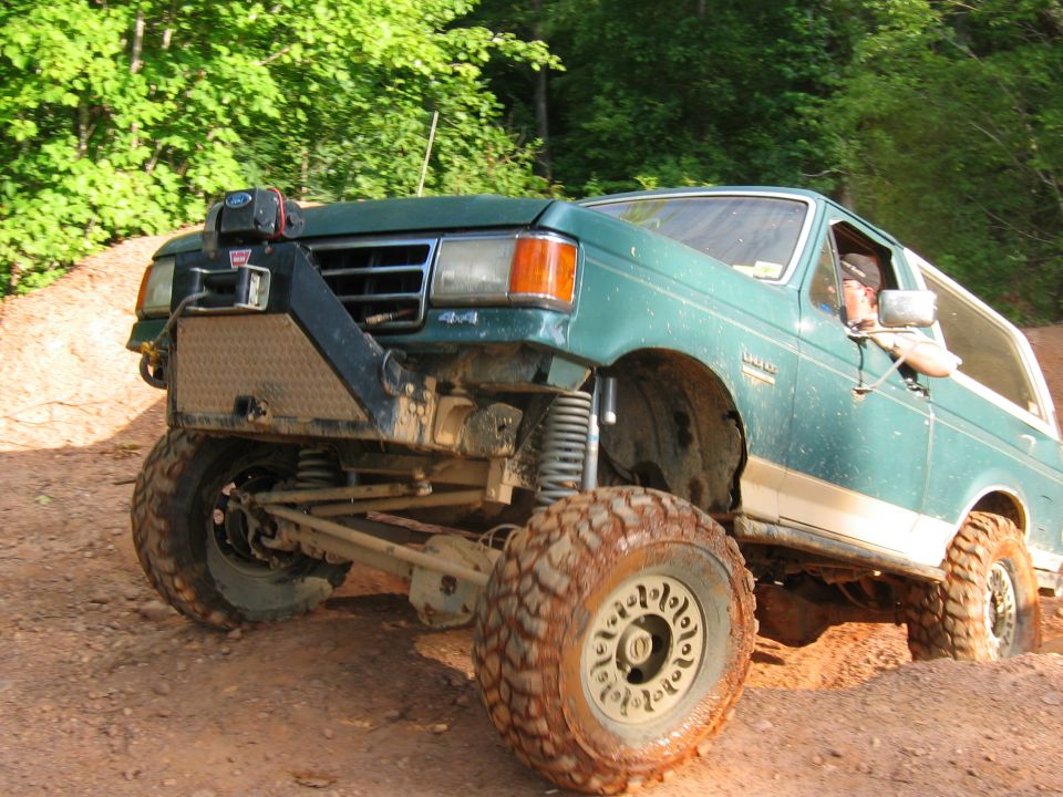 Green off-road SUV with winch and large tires on a dirt trail