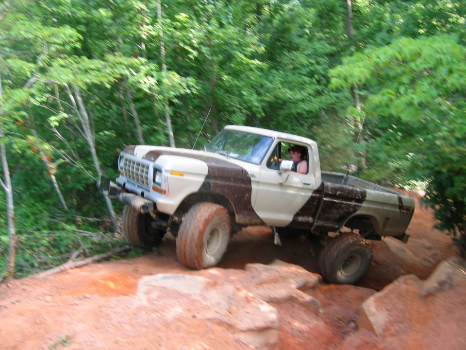 Ford F-Series pickup truck with camouflage paint driving on a dirt trail
