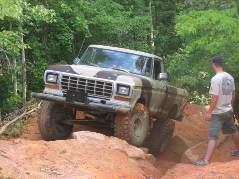 1992 Ford Mustang - A lifted Ford F-Series pickup truck with a camouflage paint scheme tackles a challenging off-road trail.