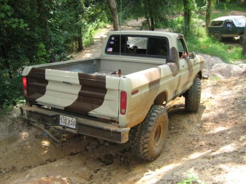 1979 Ford F-150 - A camouflaged Ford F-150 pickup truck navigates an off-road trail, with another vehicle visible in the background.