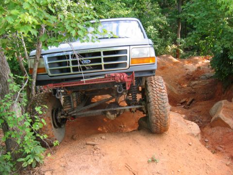 1992 Ford Mustang - This modified Ford Bronco is navigating a challenging off-road trail with steep inclines and large rocks.