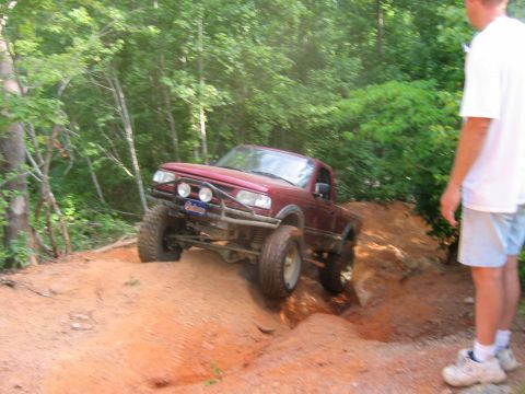 1992 Ford Mustang - Off-road pickup truck navigates a challenging dirt trail with steep inclines.