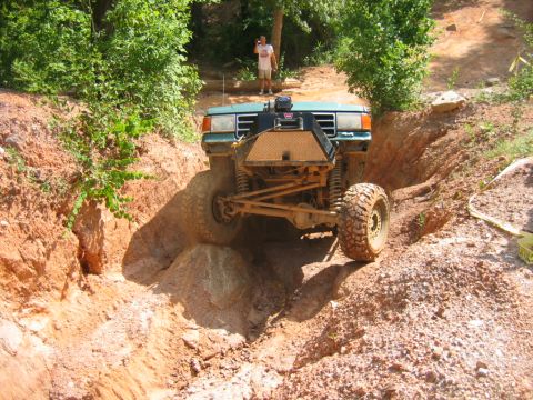 1992 Ford Mustang - A modified green off-road vehicle tackles a challenging dirt path with large tires.