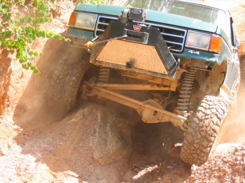 1992 Ford Mustang - Off-road truck navigating a rocky trail, kicking up dust.