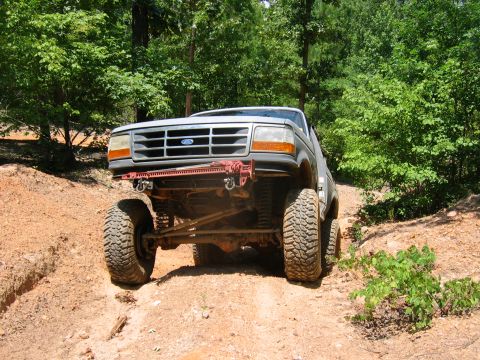1992 Ford Mustang - This lifted Ford Bronco navigates an off-road trail with a focus on its front grille and suspension system.