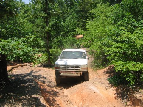 1992 Ford Mustang - This white Ford F-150 is seen driving on a dirt path surrounded by trees.