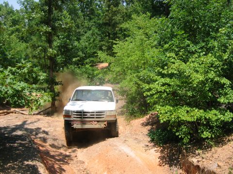 1992 Ford Mustang - A white Ford truck navigates a dusty, wooded trail. The grille design points to a 1992 model.