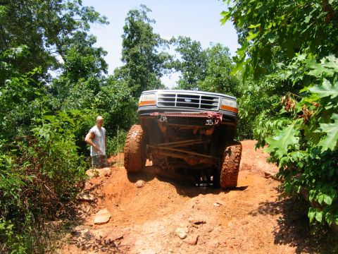1992 Ford Mustang - A lifted 1992 Ford F-Series truck navigates a challenging muddy terrain during an off-road excursion.