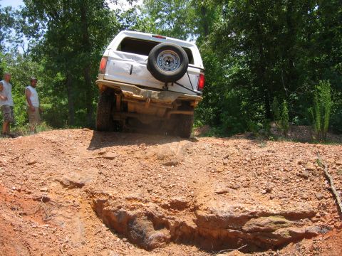 1992 Ford Mustang - A white SUV navigates a challenging dirt trail with a spare tire mounted on the back.