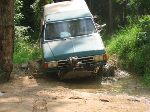 1992 Ford Mustang - This green van appears to be stuck in a muddy off-road trail, with a winch mounted on the front bumper.