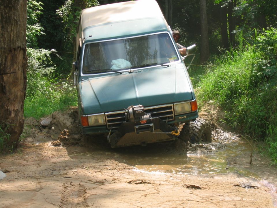 Green van with winch stuck in mud, front view
