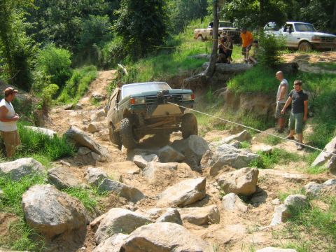 1992 Ford Mustang - Off-road truck navigating a challenging rocky course with assistance from a winch cable.