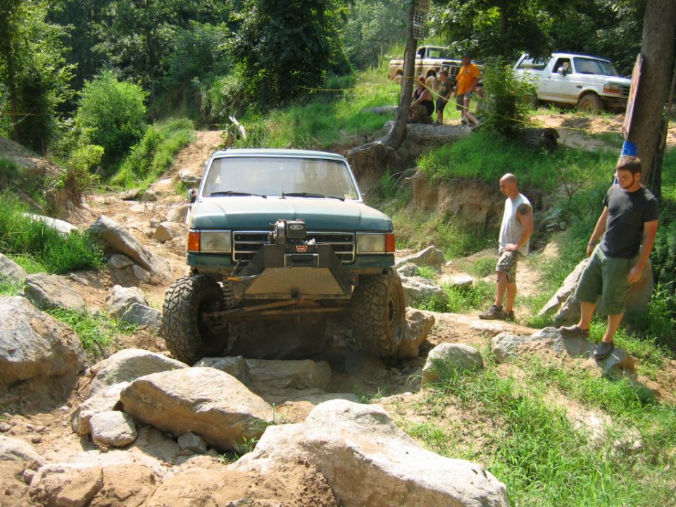 Green off-road truck with winch on rocky terrain, front view. Modified for off-roading