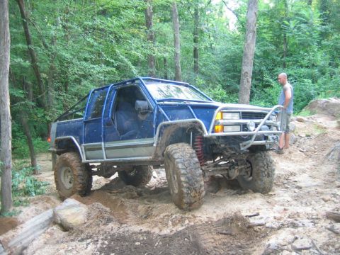 1992 Ford Mustang - Modified blue truck with a roll cage navigates a challenging off-road course.