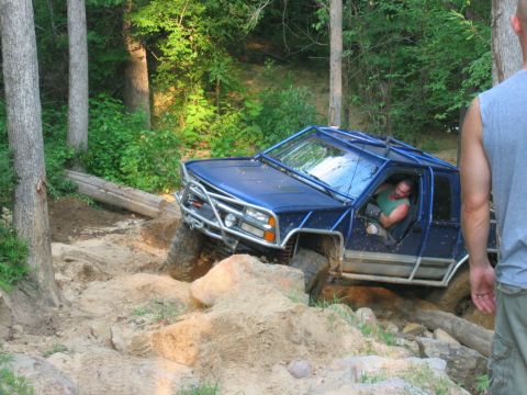1992 Ford Mustang - Off-road vehicle with custom roll cage navigating a challenging dirt and rock trail.