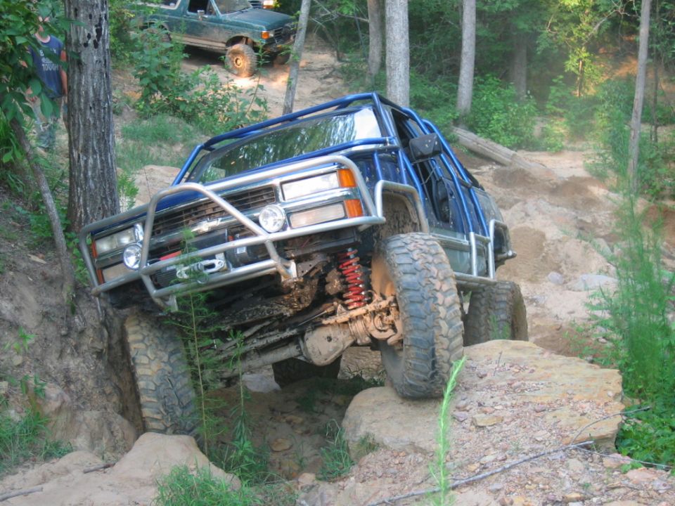 Blue off-road truck with roll cage navigating rocky terrain