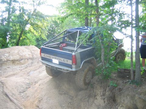1992 Ford Mustang - Off-road pickup truck navigates a steep dirt incline with a roll cage installed.