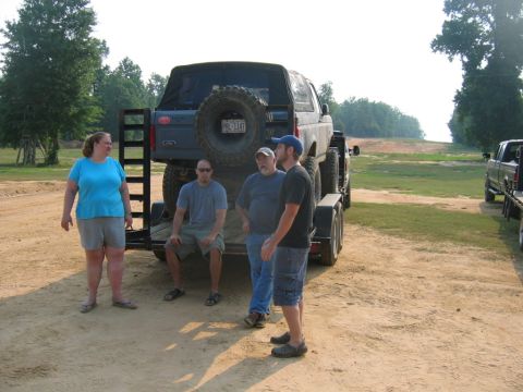 1992 Ford Mustang - A Ford Bronco is loaded onto a trailer, with several people observing. Another truck is parked nearby.