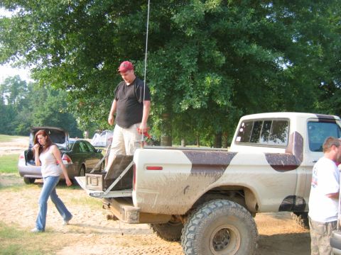1992 Ford Mustang - A group of people are gathered around a lifted pickup truck with a camouflage pattern on its bed.