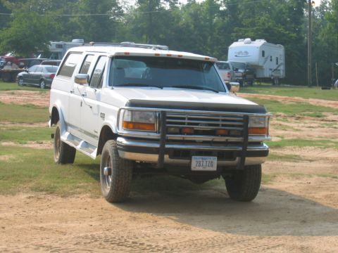 1992 Ford Mustang - This white Ford Bronco SUV is parked on a dirt lot with trees and RVs in the background.
