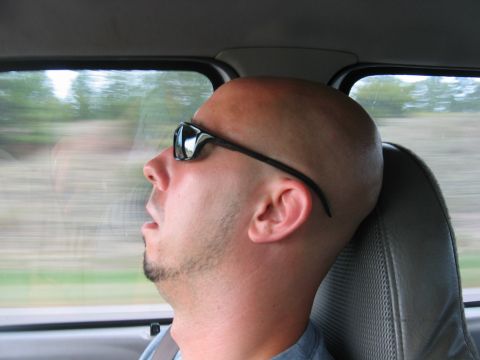 1992 Ford Mustang - A man sleeps in the passenger seat of a vehicle, his face obscured by sunglasses.