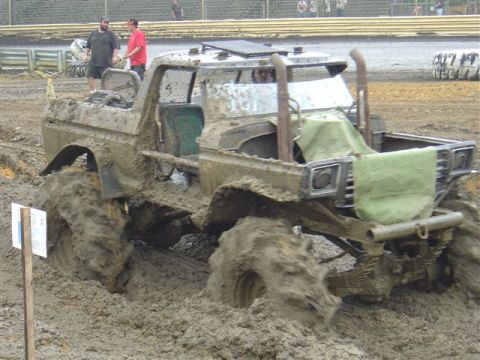 1995 Dodge 1500 - This heavily modified truck is deep in the mud, its large tires struggling for traction in a challenging off-road event.