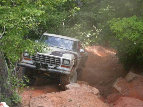 1990 Ford Bronco - This 1978 Ford Bronco navigates a challenging dirt path surrounded by trees and rocks.