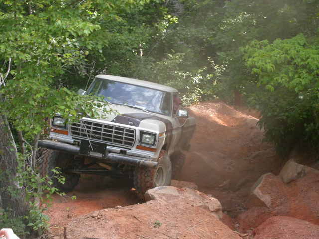 Tan and brown 1978 Ford Bronco driving on a dirt trail