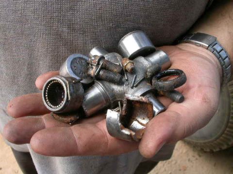 1990 Ford Bronco - A collection of worn metal automotive parts, including a universal joint and bearings, are held in a person's hand.