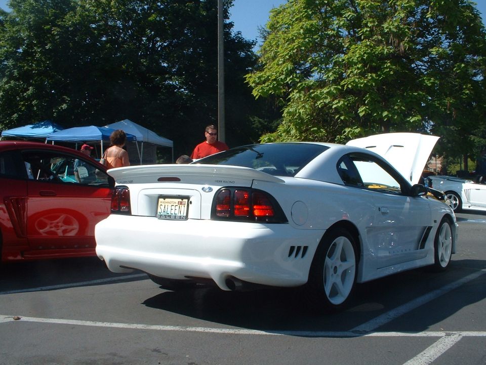 White Saleen Mustang rear view with custom bumper and spoiler. License plate reads SALEEN